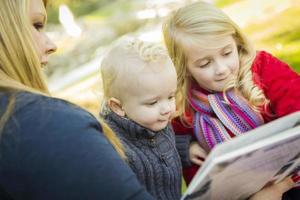 madre lettura un' libro per sua Due adorabile bionda bambini foto