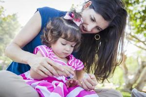 giovane madre e carino bambino ragazza l'applicazione unghia polacco foto