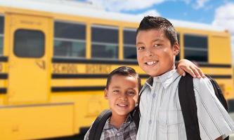 giovane ispanico ragazzi a piedi vicino scuola autobus foto