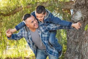 misto gara padre e figlio avendo divertimento porcellino indietro all'aperto foto