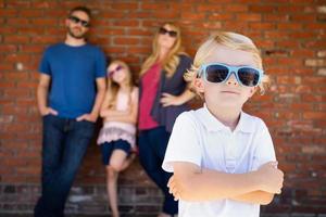carino giovane caucasico ragazzo indossare occhiali da sole con famiglia dietro a foto