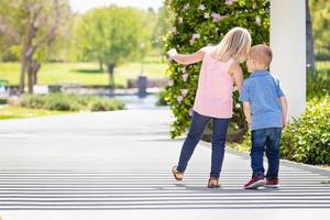 giovane sorella e fratello Tenere mani e a piedi a il parco foto
