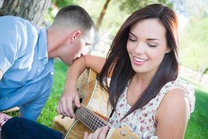 giovane adulto ragazza giocando chitarra con fidanzato nel il parco. foto