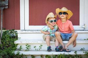 misto gara Cinese e caucasico giovane fratelli avendo divertimento indossare occhiali da sole e cowboy cappelli foto