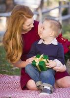 giovane ragazzo Tenere Natale regalo con il suo mamma nel parco foto