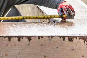 cemento costruzione lavoratore utilizzando misurazione nastro mentre formatura piscina cimasa foto