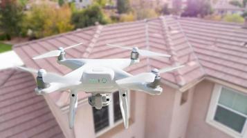 senza equipaggio aereo sistema UAV quadcopter fuco nel il aria al di sopra di Casa ispezionando il tetto foto