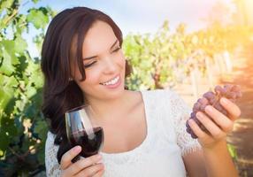 bellissimo giovane adulto donna godendo bicchiere di vino degustazione a piedi nel il vigneto foto