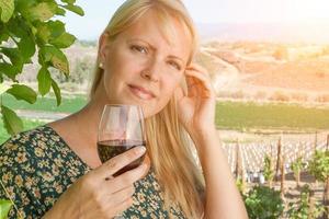 bellissimo giovane adulto donna godendo bicchiere di vino degustazione nel il vigneto foto