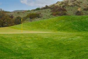 panoramico erboso golf corso verde e bandiera. foto