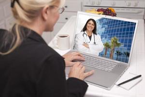 donna nel cucina utilizzando il computer portatile - in linea con infermiera o medico foto