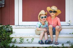 misto gara Cinese e caucasico giovane fratelli avendo divertimento indossare occhiali da sole e cowboy cappelli foto