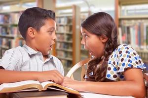 ispanico ragazzo e ragazza avendo divertimento studiando insieme nel il biblioteca foto