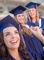 contento laurea gruppo di ragazze nel berretto e toga festeggiare su città universitaria. foto