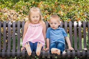 giovane sorella e fratello avendo divertimento su il panchina a il parco foto