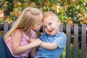 giovane sorella e fratello avendo divertimento su il panchina a il parco foto