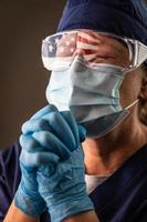 americano bandiera riflettendo su afflitto preghiere femmina medico lavoratore indossare protettivo viso maschera e occhiali foto
