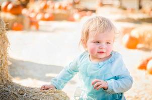 adorabile bambino ragazza avendo divertimento nel un' rustico ranch ambientazione a il zucca toppa. foto