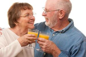 contento anziano coppia con bicchieri di arancia succo foto