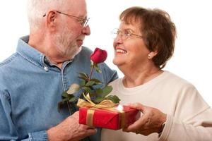 contento anziano coppia con regalo e rosso rosa foto