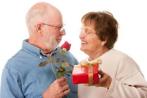 contento anziano coppia con regalo e rosso rosa foto