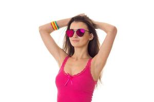 bellissimo giovane ragazza nel un' luminosa rosa camicia e bicchieri sollevato sua mani su foto