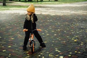 carino poco ragazza cavalcate su bicicletta a il parco foto