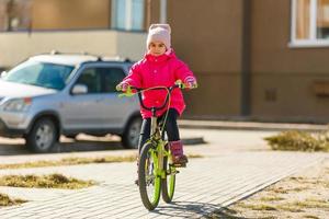 poco ragazza equitazione bicicletta nel città parco. foto