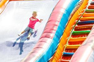 contento poco ragazza avendo molte di divertimento su un' salto castello durante scorrevole. foto