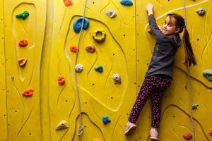 poco ragazza arrampicata un' roccia parete interno. foto