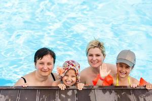 contento famiglia nel il piscina, avendo divertimento nel il acqua, madre con bambini godendo acqua parco, spiaggia ricorrere, estate vacanze, vacanza concetto foto