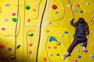 poco ragazza arrampicata un' roccia parete interno. foto