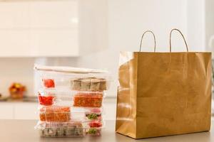 Sushi rotoli nel plastica scatola vicino carta pacchetto su bianca tavolo. consegna. prendere lontano. foto