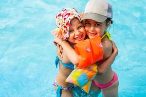 bambini giocando nel piscina. Due poco ragazze avendo divertimento nel il piscina. estate vacanze e vacanza concetto foto