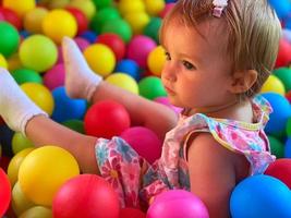 bella poco bambino ragazza avendo divertimento nel il palla piscina foto