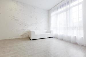 interno di vivente camera moderno stile con tessuto divano, lato tavolo e vuoto bianca parete su legna pavimento foto