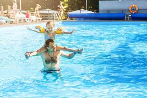 poco ragazza e contento papà avendo divertimento insieme nel all'aperto nuoto piscina foto