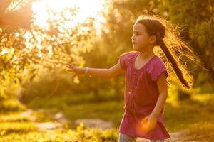 cinque anni vecchio caucasico bambino ragazza soffiaggio sapone bolle all'aperto a tramonto - contento spensierato infanzia. foto