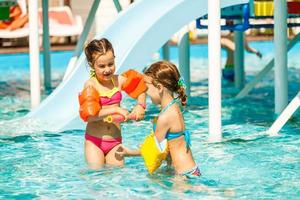 Due poco bambini giocando nel il nuoto piscina foto