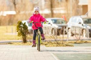 poco ragazza equitazione bicicletta nel città parco. foto