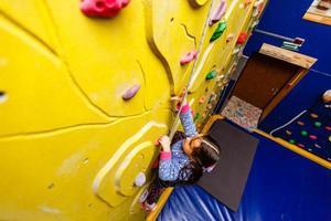 poco ragazza arrampicata un' roccia parete interno. foto