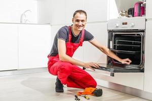 giovane uomo riparazione forno nel cucina foto