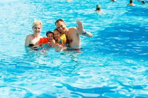 contento famiglia nel il piscina, avendo divertimento nel il acqua, madre con bambini godendo acqua parco, spiaggia ricorrere, estate vacanze, vacanza concetto foto