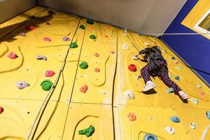 poco ragazza su arrampicata nel divertimento centro. foto