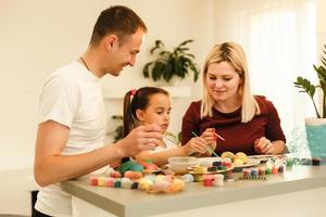 contento Pasqua famiglia madre, padre e bambini avendo divertimento dipingere e decorare uova per vacanza foto