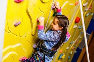 poco ragazza arrampicata un' roccia parete interno. foto