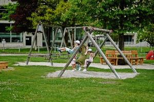 madre con bambini oscillante nel terreno di gioco a Hallstatt, Austria. foto