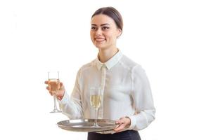 giovane ragazza-cameriere nel un' bianca camicia Tenere un' bicchiere di vino e sorridente foto