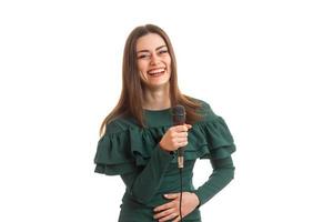 contento donna ridendo con microfono nel mani nel verde vestito foto