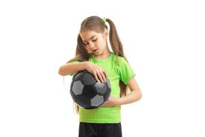 giovane poco ragazza nel verde camicia con calcio palla nel mani foto